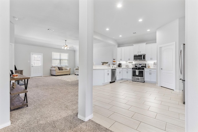 kitchen featuring light carpet, ceiling fan, tasteful backsplash, white cabinetry, and stainless steel appliances