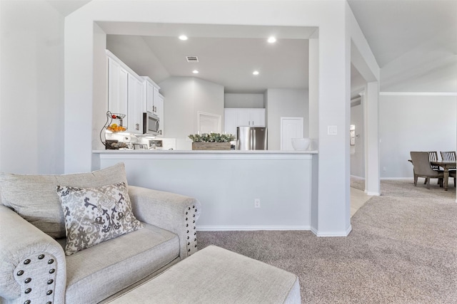 kitchen featuring white cabinets, light colored carpet, vaulted ceiling, and appliances with stainless steel finishes