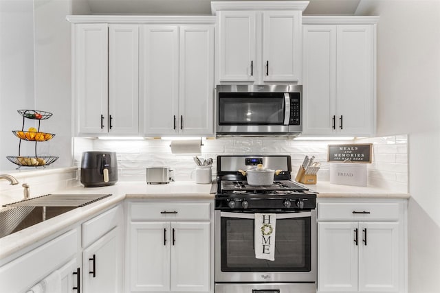 kitchen with tasteful backsplash, white cabinetry, sink, and stainless steel appliances