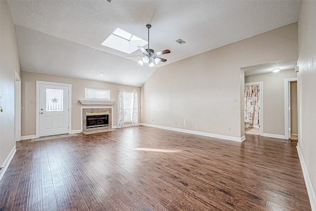 unfurnished living room featuring ceiling fan, dark hardwood / wood-style floors, lofted ceiling with skylight, and a fireplace