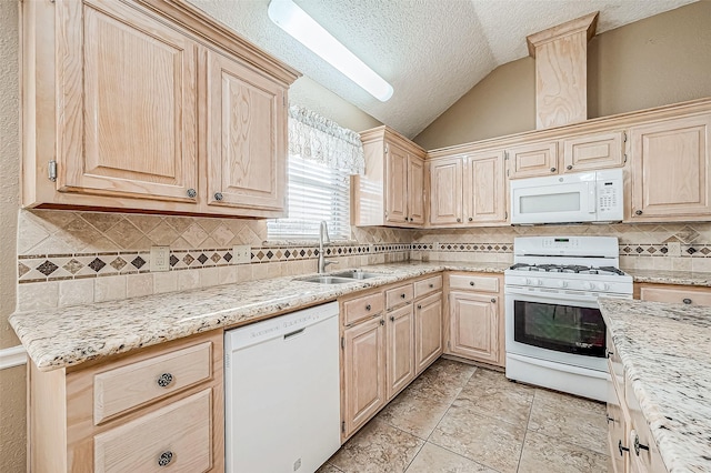 kitchen featuring vaulted ceiling, light stone countertops, sink, and white appliances