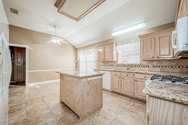 kitchen featuring vaulted ceiling, a kitchen island, light brown cabinets, and white appliances