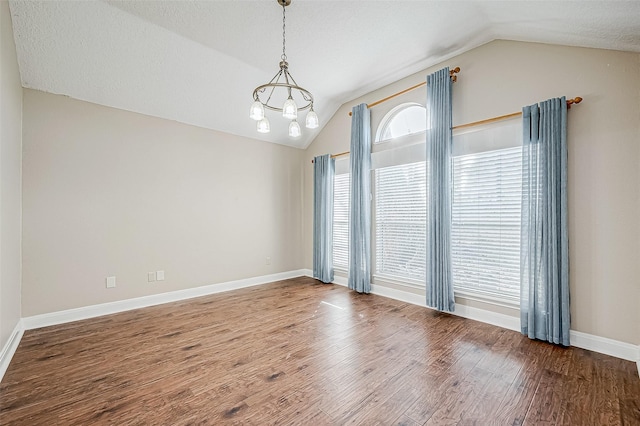 empty room featuring lofted ceiling, a textured ceiling, a chandelier, and hardwood / wood-style flooring