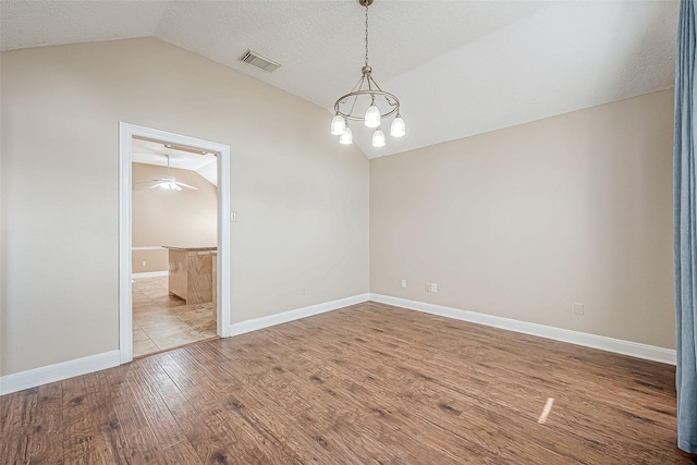 spare room with vaulted ceiling, a textured ceiling, ceiling fan with notable chandelier, and light wood-type flooring