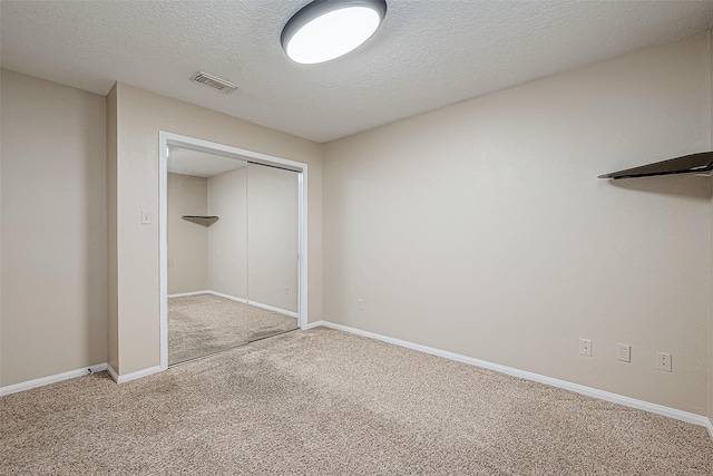 unfurnished bedroom featuring a closet, a textured ceiling, and carpet flooring