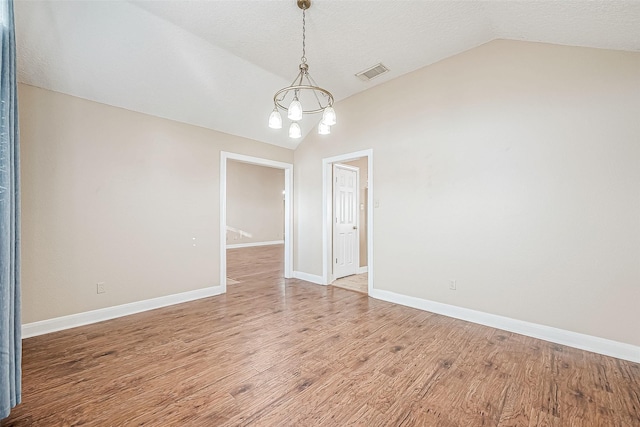 unfurnished room featuring a textured ceiling, a chandelier, lofted ceiling, and hardwood / wood-style floors