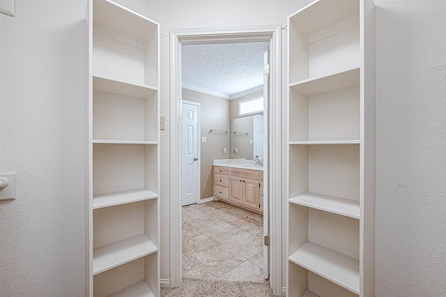 bathroom featuring a textured ceiling, ornamental molding, and vanity