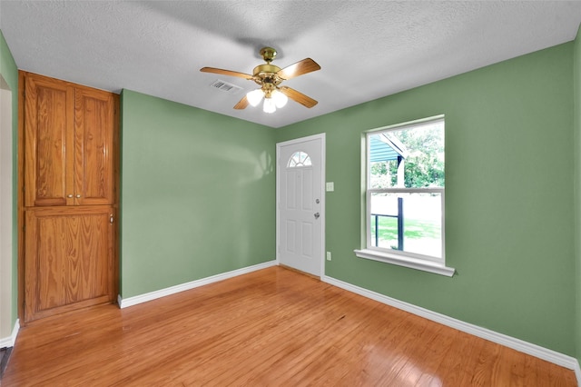 foyer entrance with ceiling fan, light wood-type flooring, and a textured ceiling