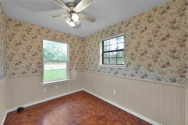 empty room featuring a textured ceiling, dark parquet floors, and ceiling fan