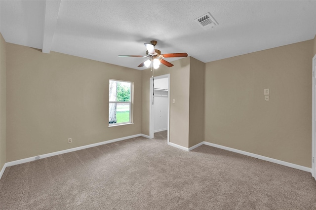 empty room with ceiling fan, light colored carpet, and a textured ceiling