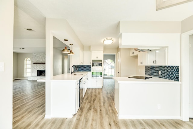 kitchen with decorative light fixtures, kitchen peninsula, sink, stainless steel appliances, and white cabinets