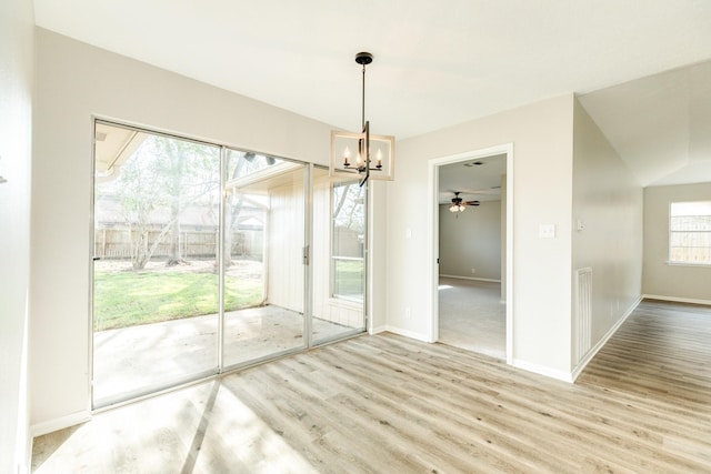 unfurnished dining area with ceiling fan with notable chandelier and light hardwood / wood-style flooring