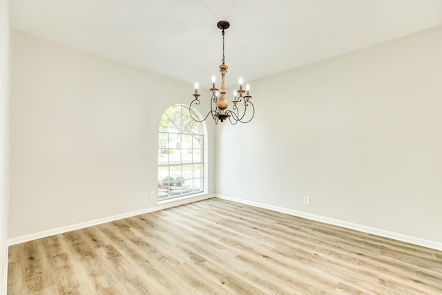 empty room featuring a chandelier and light hardwood / wood-style flooring