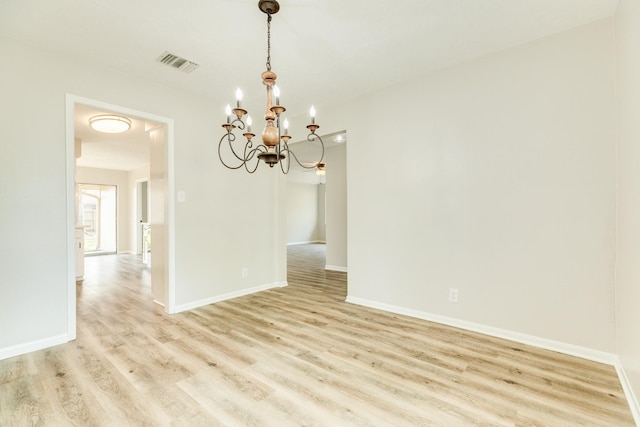 spare room with light hardwood / wood-style floors and a chandelier