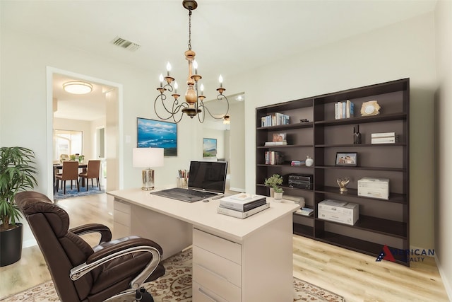 home office featuring light wood-type flooring and a notable chandelier