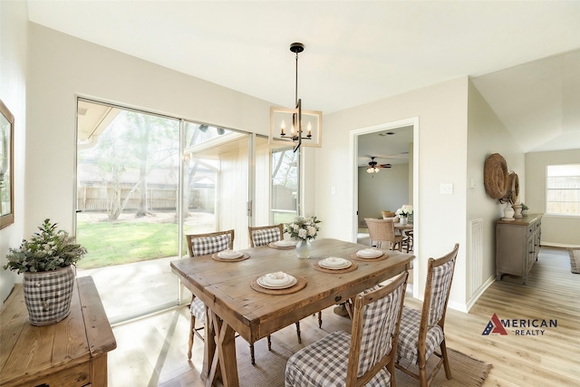 dining space with ceiling fan with notable chandelier and light hardwood / wood-style flooring