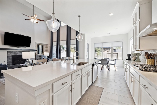 kitchen with a center island with sink, white cabinets, sink, wall chimney exhaust hood, and stainless steel appliances