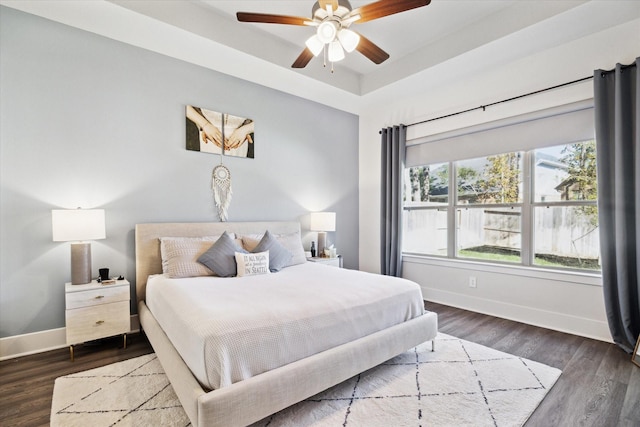 bedroom with a tray ceiling, ceiling fan, and dark hardwood / wood-style floors