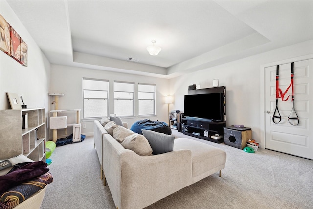 living room with a tray ceiling and light colored carpet