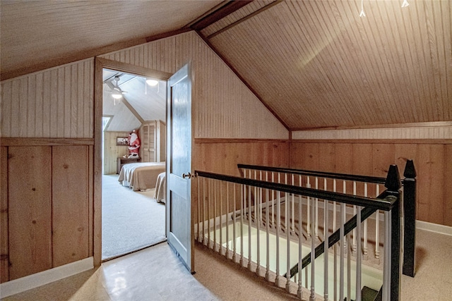 interior space featuring ceiling fan, wood walls, light colored carpet, and vaulted ceiling