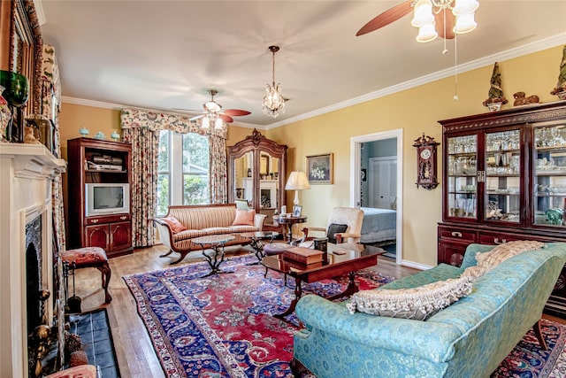 living room featuring hardwood / wood-style floors, ceiling fan, a premium fireplace, and crown molding