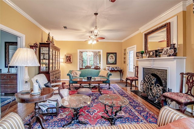 living room featuring hardwood / wood-style flooring, ceiling fan, crown molding, and a premium fireplace