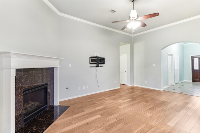 unfurnished living room featuring light wood-type flooring, ornamental molding, and a tiled fireplace