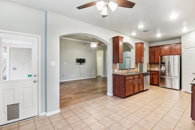 kitchen with sink, tasteful backsplash, dark stone counters, light tile patterned flooring, and appliances with stainless steel finishes