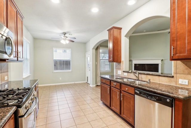 kitchen with ceiling fan, sink, dark stone counters, and appliances with stainless steel finishes