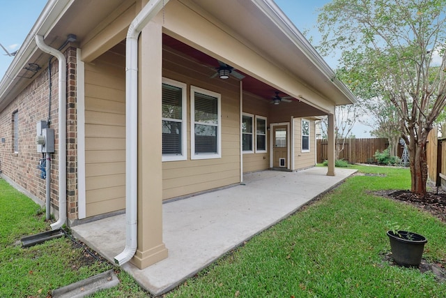 rear view of property featuring ceiling fan, a patio area, and a lawn