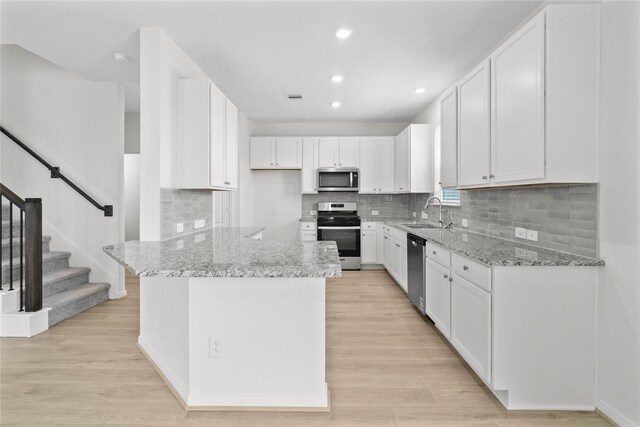 2836 Shimmer Edge Dr, Katy, TX 77493 - kitchen with a sink, appliances with stainless steel finishes, light stone countertops, and white cabinetry