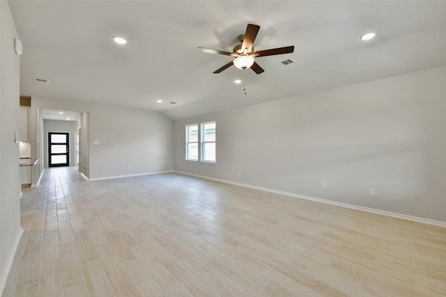 empty room with ceiling fan, light hardwood / wood-style flooring, and vaulted ceiling