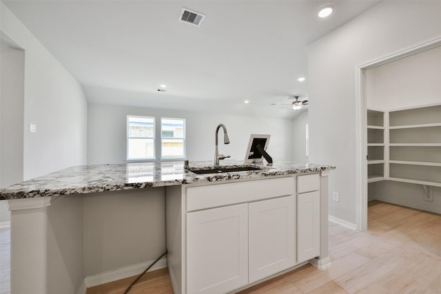 kitchen with light stone countertops, ceiling fan, sink, light hardwood / wood-style flooring, and white cabinets