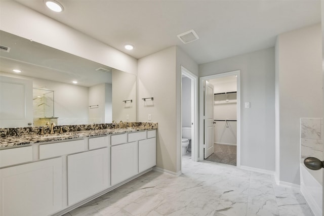 bathroom featuring a shower with door, vanity, and toilet