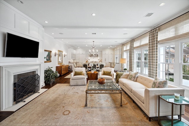 living room with beamed ceiling, hardwood / wood-style floors, and a chandelier