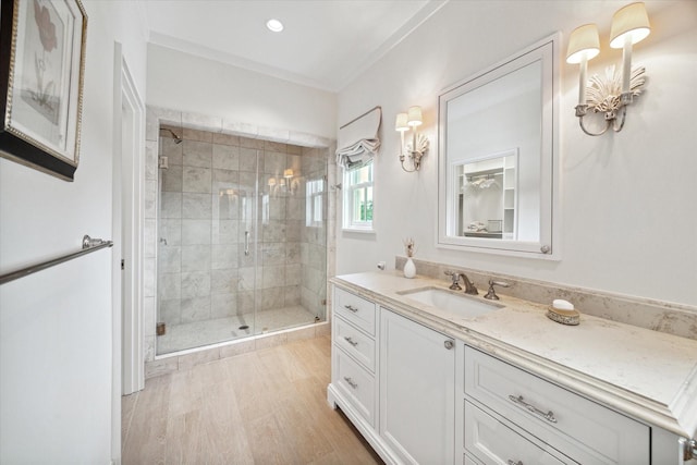 bathroom featuring wood-type flooring, vanity, walk in shower, and ornamental molding