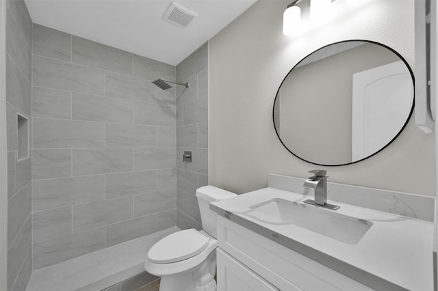 bathroom featuring vanity, toilet, and a tile shower