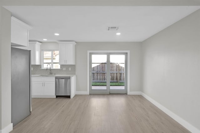 kitchen featuring backsplash, white cabinetry, a healthy amount of sunlight, and stainless steel appliances