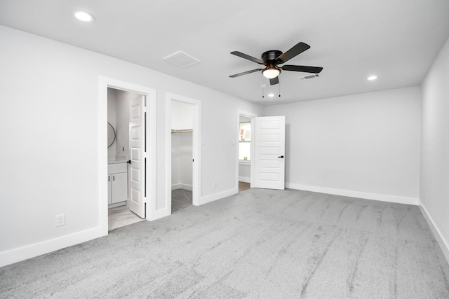 unfurnished bedroom with ensuite bath, a spacious closet, ceiling fan, light colored carpet, and a closet