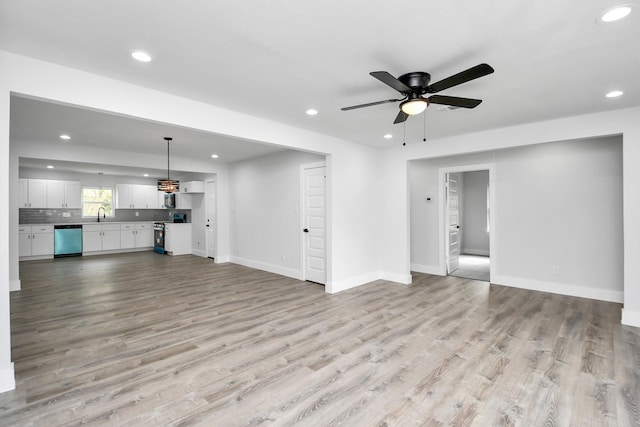 unfurnished living room featuring ceiling fan, sink, and light hardwood / wood-style flooring