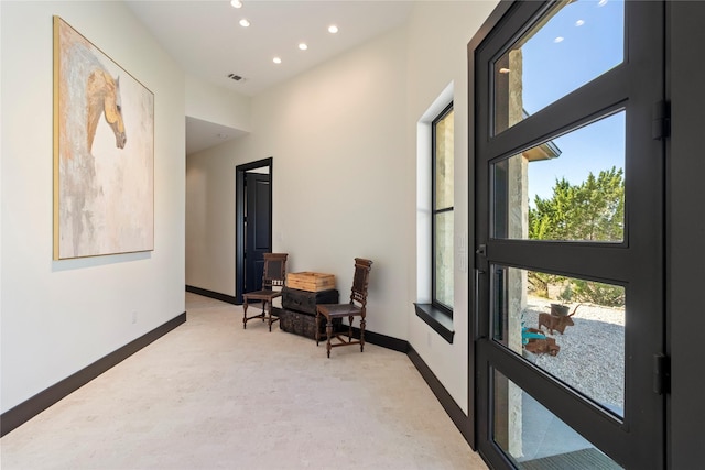 hallway featuring a towering ceiling and light colored carpet