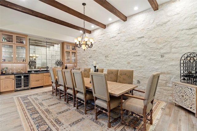 dining area with indoor bar, light wood-type flooring, beam ceiling, beverage cooler, and a chandelier