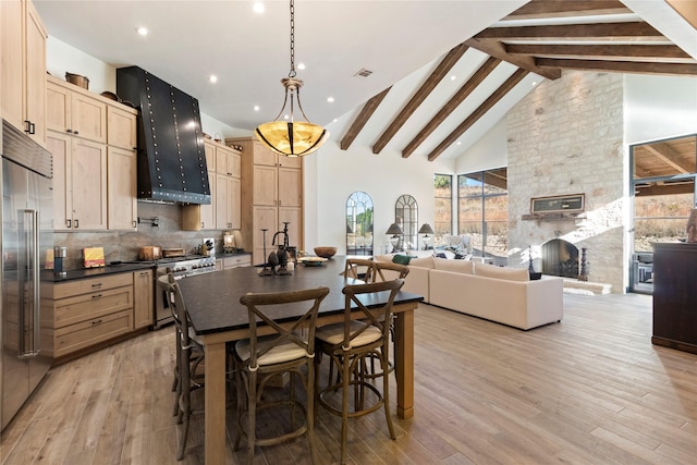 dining room featuring beamed ceiling, light hardwood / wood-style flooring, high vaulted ceiling, and a stone fireplace