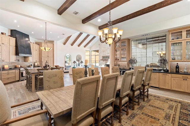 dining room featuring lofted ceiling with beams, light wood-type flooring, and a notable chandelier