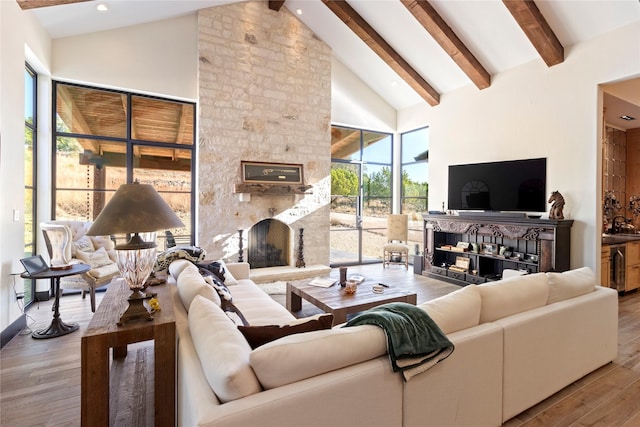 living room featuring beam ceiling, light wood-type flooring, a fireplace, and high vaulted ceiling