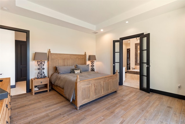 bedroom featuring a raised ceiling and connected bathroom