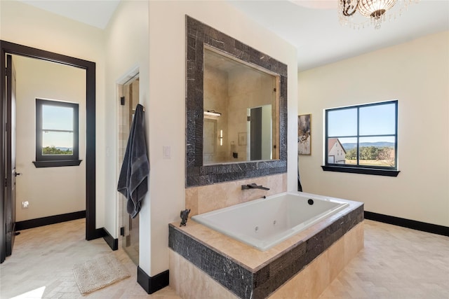 bathroom with separate shower and tub and a notable chandelier