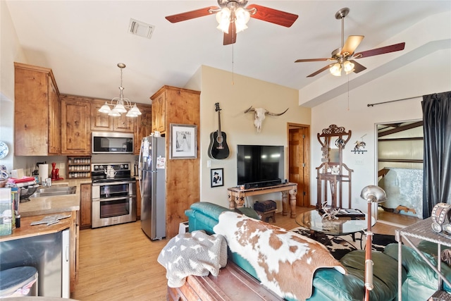 kitchen featuring pendant lighting, vaulted ceiling, light hardwood / wood-style floors, stainless steel appliances, and a chandelier