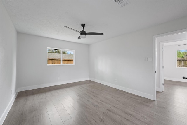 spare room with a wealth of natural light, ceiling fan, and wood-type flooring