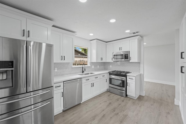 kitchen featuring sink, white cabinets, light hardwood / wood-style flooring, and appliances with stainless steel finishes